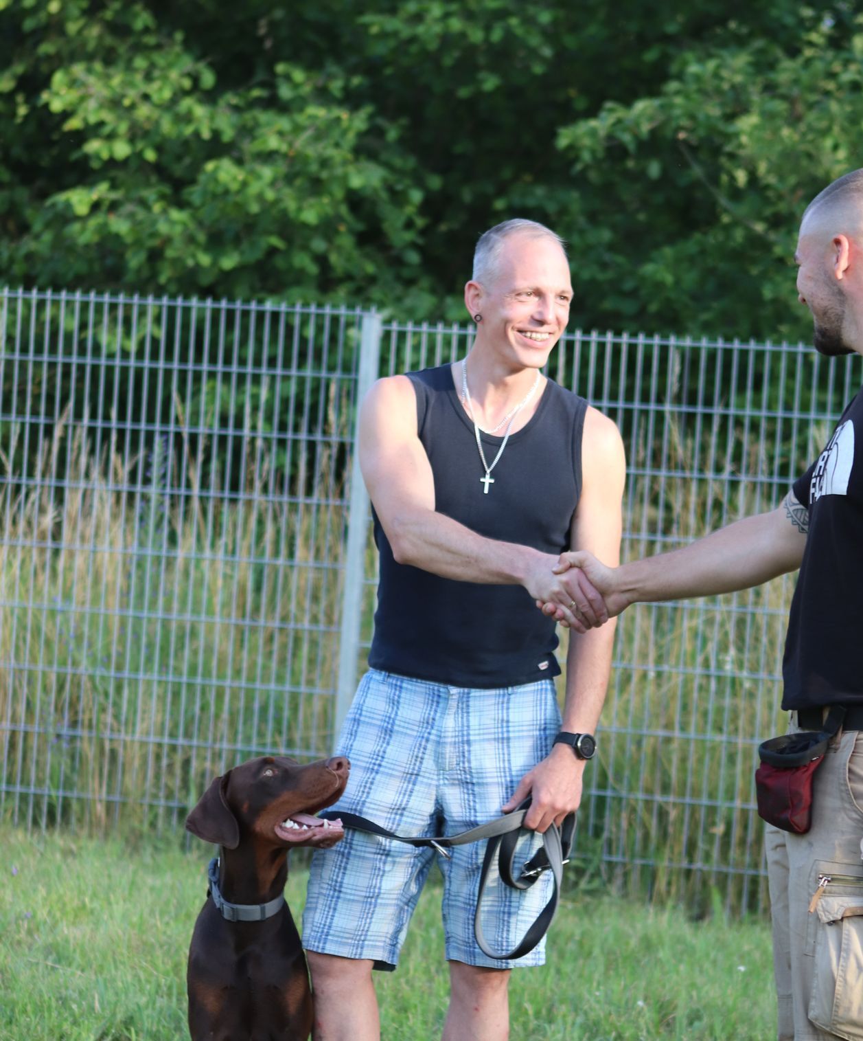 Zufriedener Hundehalter gibt Leon Weisbecker nach dem Training die Hand, sein Hund sitzt aufmerksam daneben